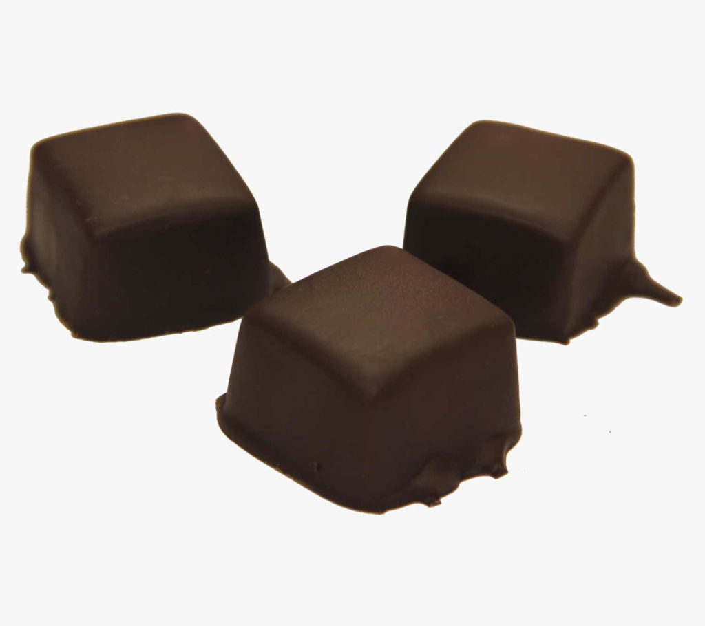 Three hand-dipped dark chocolate caramels on a white background