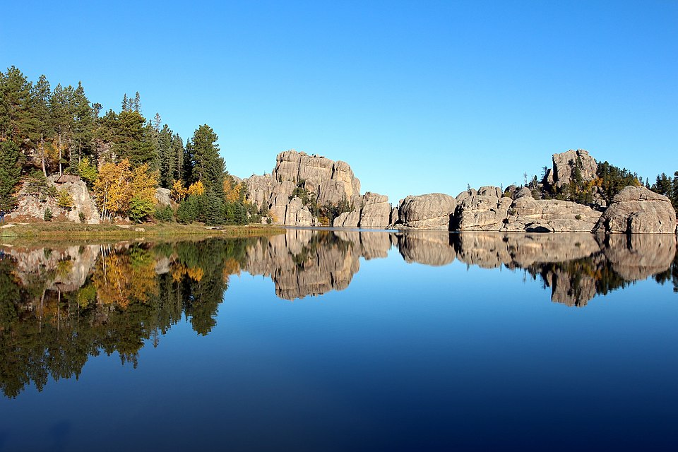 Sylvan Lake in October with golden aspens and granite boulders reflected in still water, Custer State Park, South Dakota